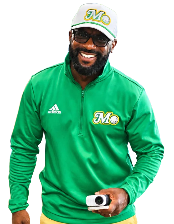Johnny Palmer, founder of the Palmer Youth Golf Association, in a green Mo City Golf quarter-zip and hat