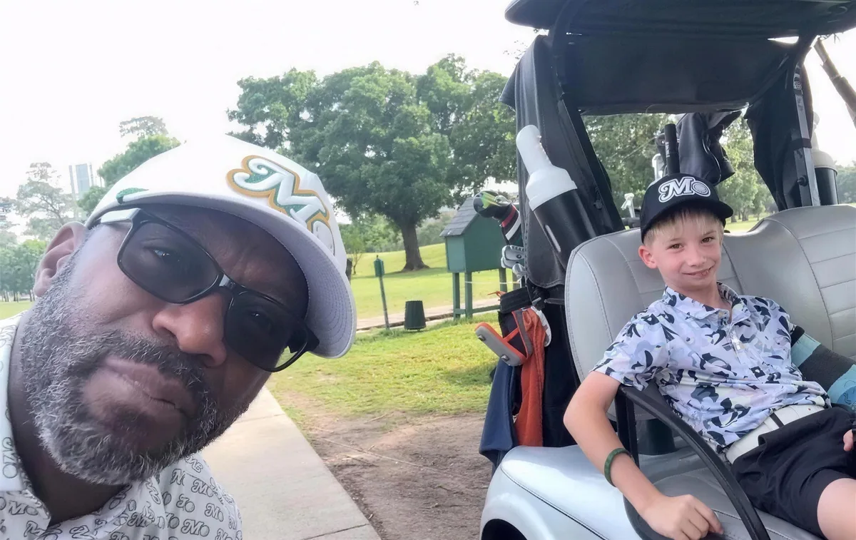 A golfer in a Mo hat and a junior golfer in a golf cart
