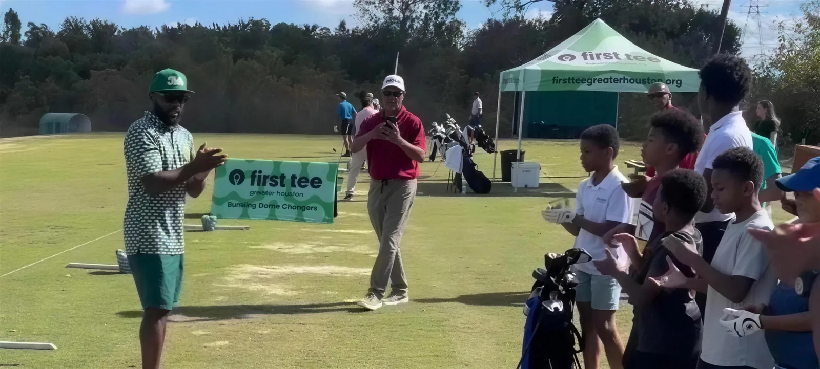 Junior golfers clapping during a clinic on the range
