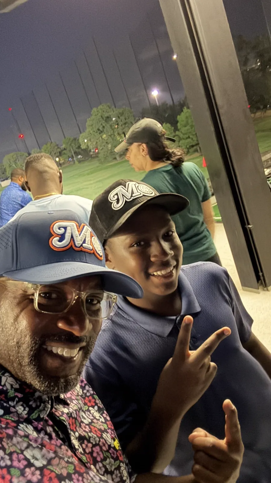 Golfers in Mo hats at the range at night