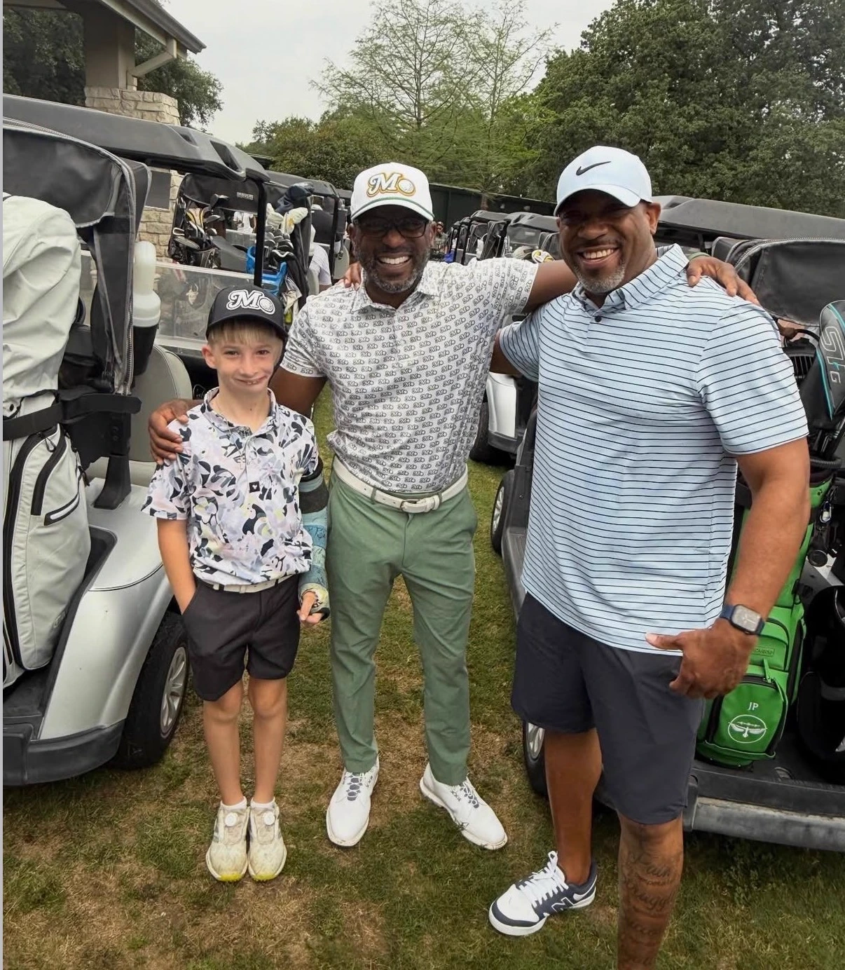 A junior golfer and two adults in Mo City gear arm in arm by the golf carts